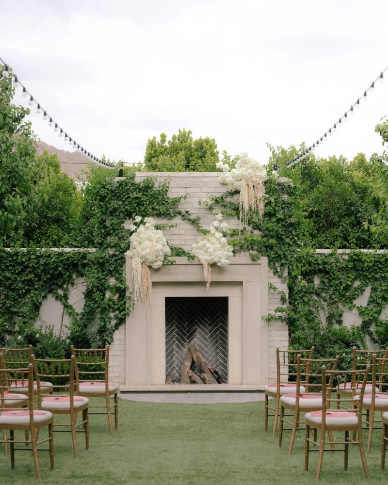 Garden ceremony set before an ivy-covered fireplace