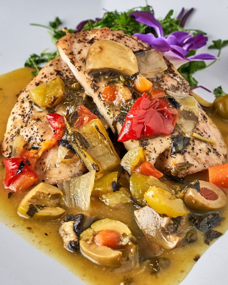 Roasted chicken with peppers, olives and mushrooms, garnished with orchids